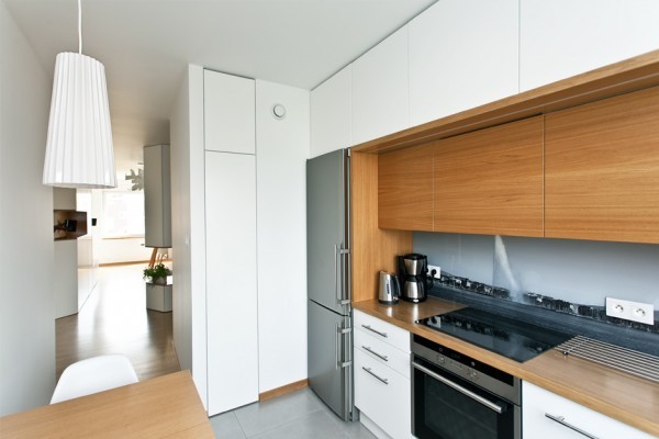 The kitchen is quite narrow but meticulously organized with a large shelving unit and plenty of cabinetry. The backsplash is decorated with a Geneva cityscape to recall memories of a place where the apartment's owner spent time.