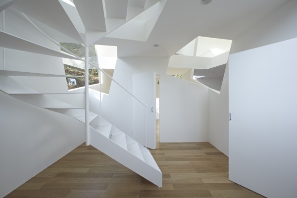 The spiral staircase uses long, thin slats for each step and barely-there white railings. The distinctive way that the stairs turn is nearly reminiscent of an Escher staircase.