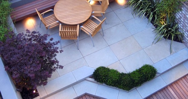 Planters can also be built right into the patio to blur the edges between zones. Note the beautiful selection of different colored leaves; not all color in a garden needs to come from flowers. In this design the built-in bench has been utilized as extra seating at the table–great for unexpected guests!