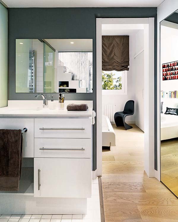 The bathroom, located just behind the stairs, is a simple white tiled area decorated with rich, chocolate brown towels.