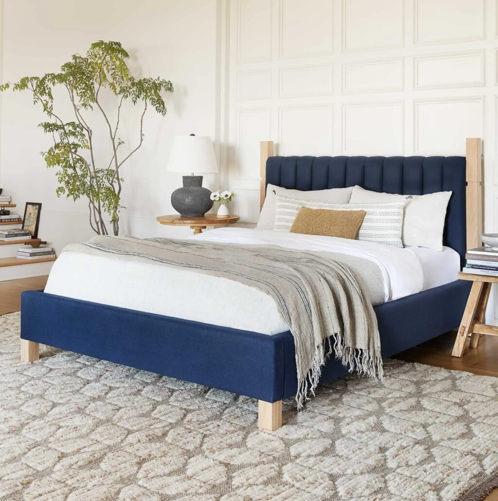 California king tufted bed with light natural wood framing dark blue